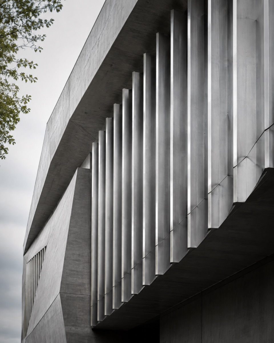 Illustrative Architekturaufnahme: klare Betonflächen und metallische Lamellen im Tageslicht